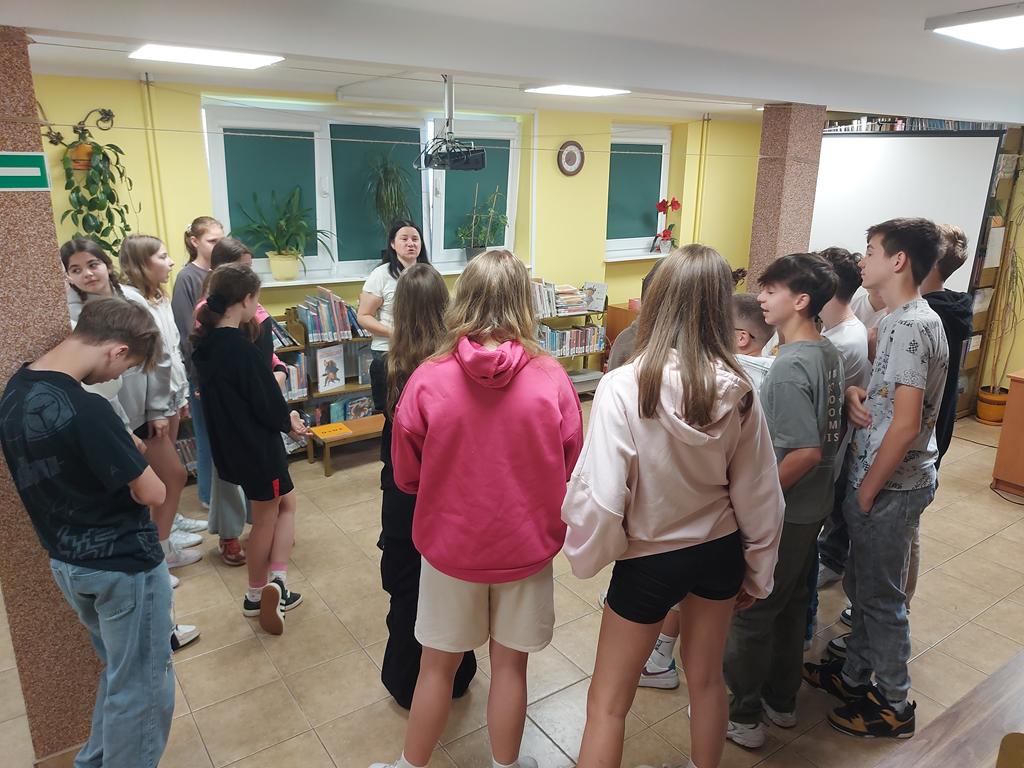 Dzieci przemieściły się i stoją przed prowadzącą w trzech grupach po kilka osób.