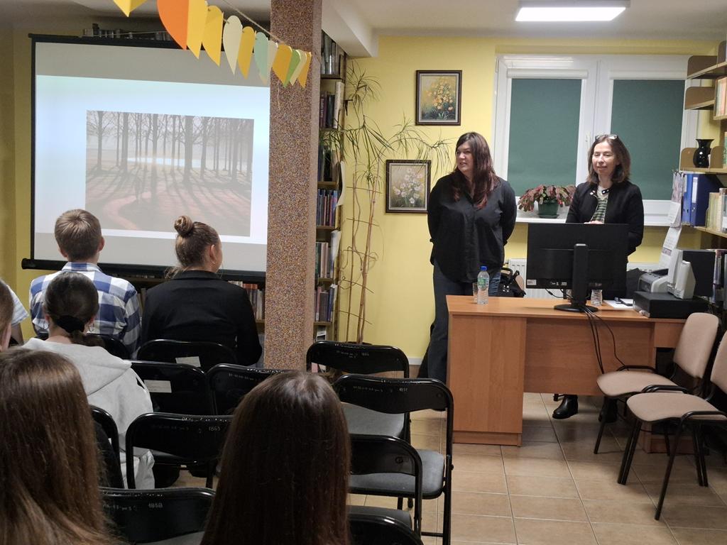 Jeden chłopak i cztery dziewczyny siedzą na krzesłach. Przed nimi stoją za biurkiem dwie kobiety w ciemnych ubraniach. Obok kobiet stoi ekran rzutnika, na którym jest wyświetlana prezentacja dotycząca depresji.